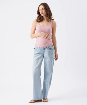 Woman wearing a pink tank top and light blue jeans on a white background