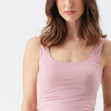 Woman wearing a light pink tank top against a plain background