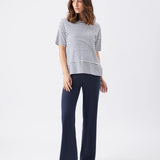 Woman wearing a striped shirt and navy pants on a white background