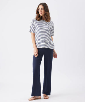 Woman wearing a striped shirt and navy pants on a white background