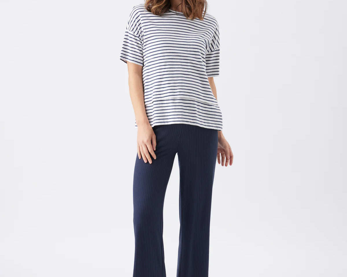 Woman wearing a striped shirt and navy pants on a white background