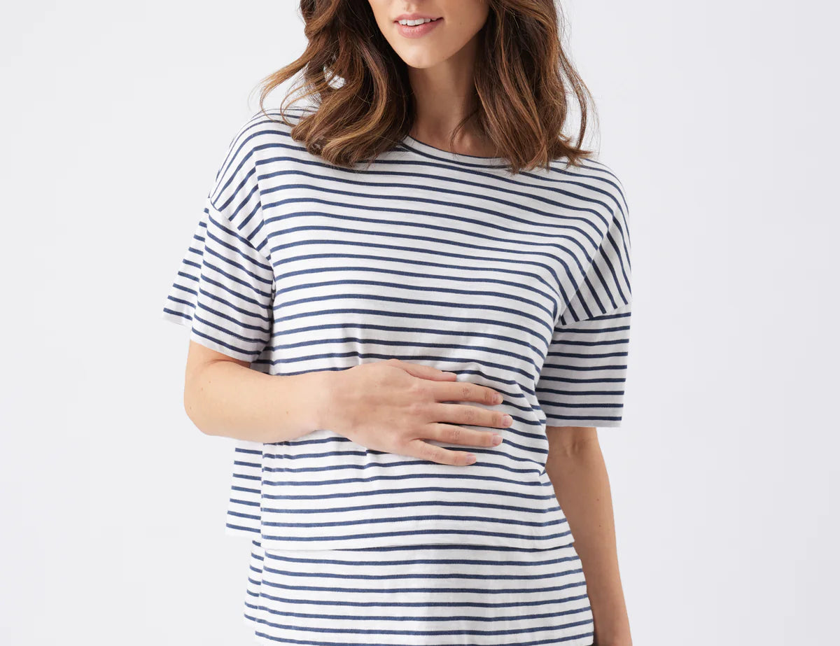 Woman wearing a navy and white striped shirt with navy pants on a white background