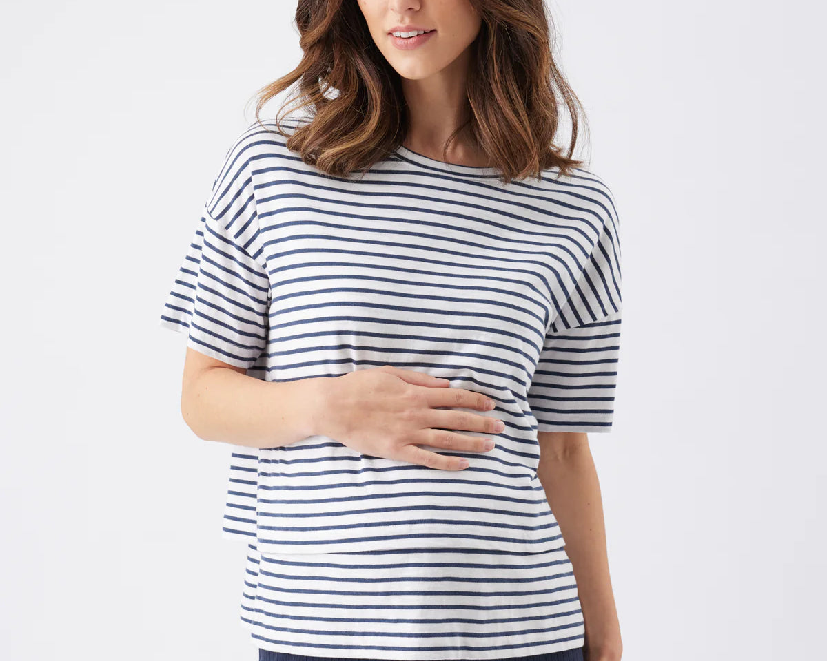 Woman wearing a navy and white striped shirt with navy pants on a white background