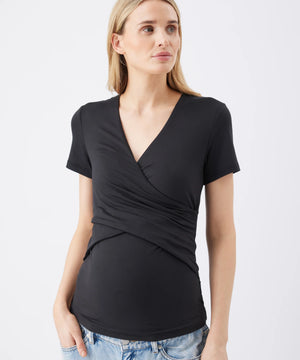 Woman wearing a black wrap-style top with short sleeves on a white background