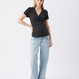 Woman wearing a black top and light blue jeans on a white background
