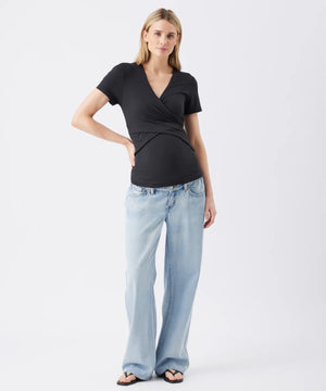 Woman wearing a black top and light blue jeans on a white background