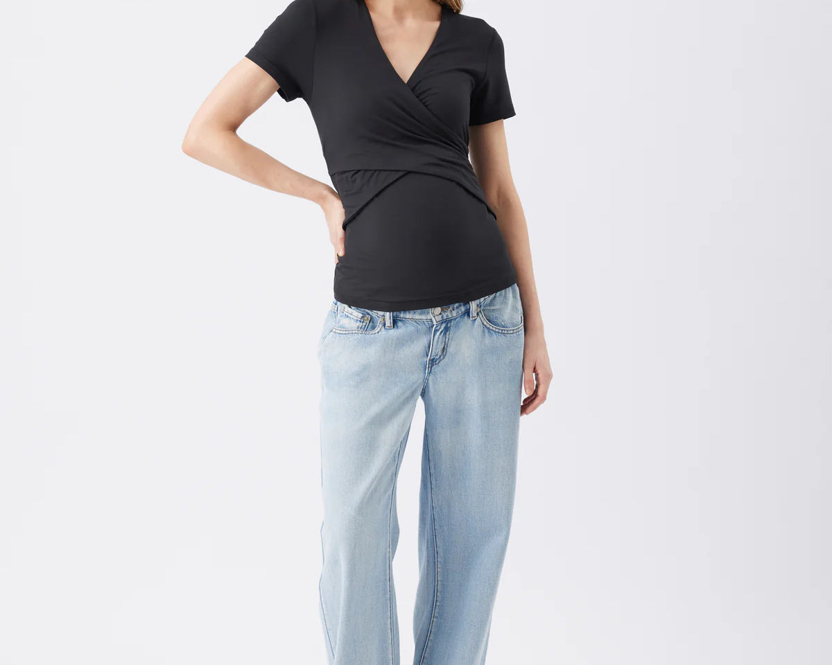 Woman wearing a black top and light blue jeans on a white background