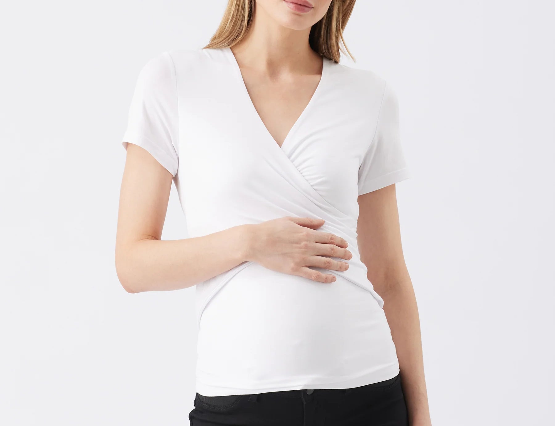 Woman wearing a white short-sleeve top and black pants on a white background