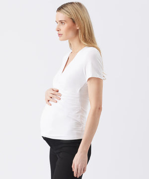 Woman wearing a white V-neck top on a plain background