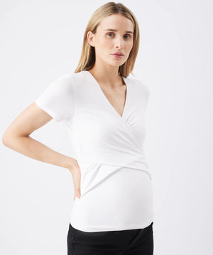 Woman wearing a white wrap top with a plain background