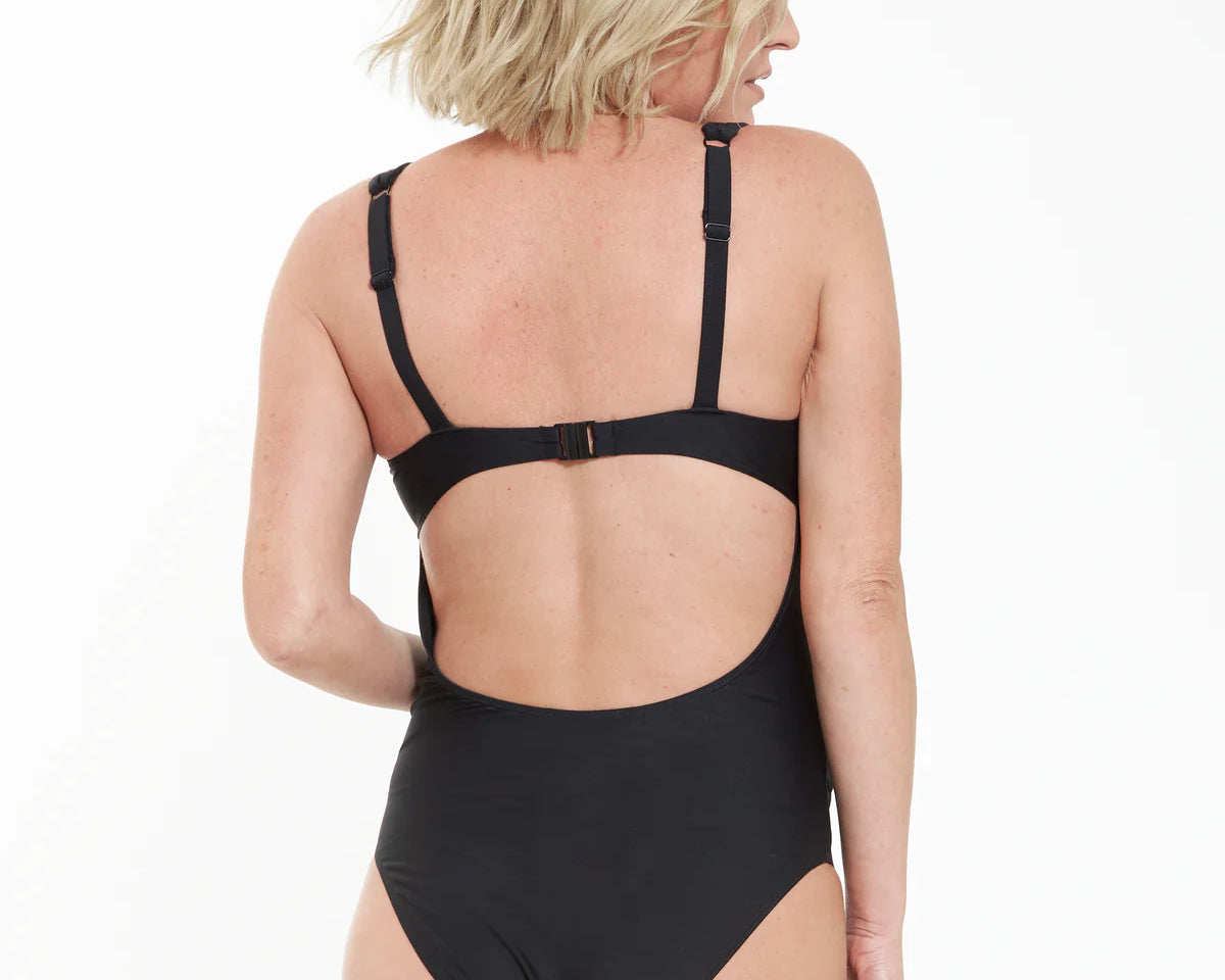 Woman wearing a black swimsuit with cut-out design on a white background