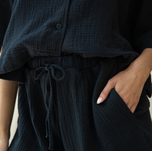 Person wearing a dark textured outfit with a drawstring waist.