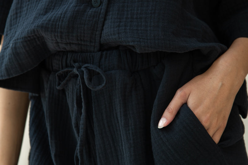 Person wearing a dark textured outfit with a drawstring waist.