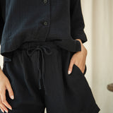 Person wearing a black outfit with shorts and a top, standing against a neutral background.
