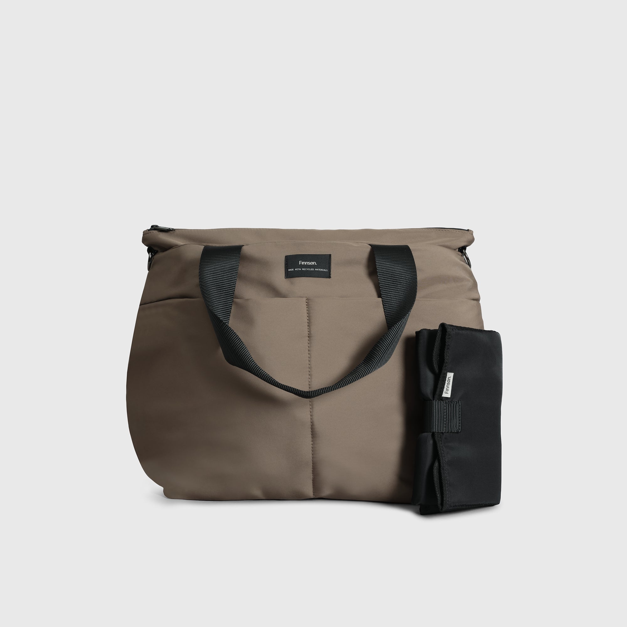 Sigrid Eco Changing Bag in Mocha, front view with handles folded forward and black changing mat standing beside it