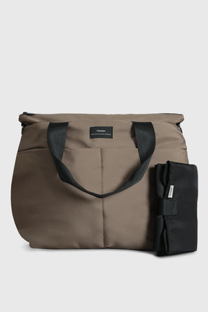 Sigrid Eco Changing Bag in Mocha, front view with handles folded forward and black changing mat standing beside it