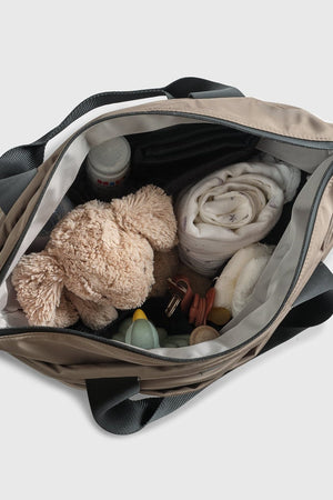 Sigrid Eco Changing Bag in Mocha open from above, showing a soft toy, muslin, nappy, bottle and dummies inside