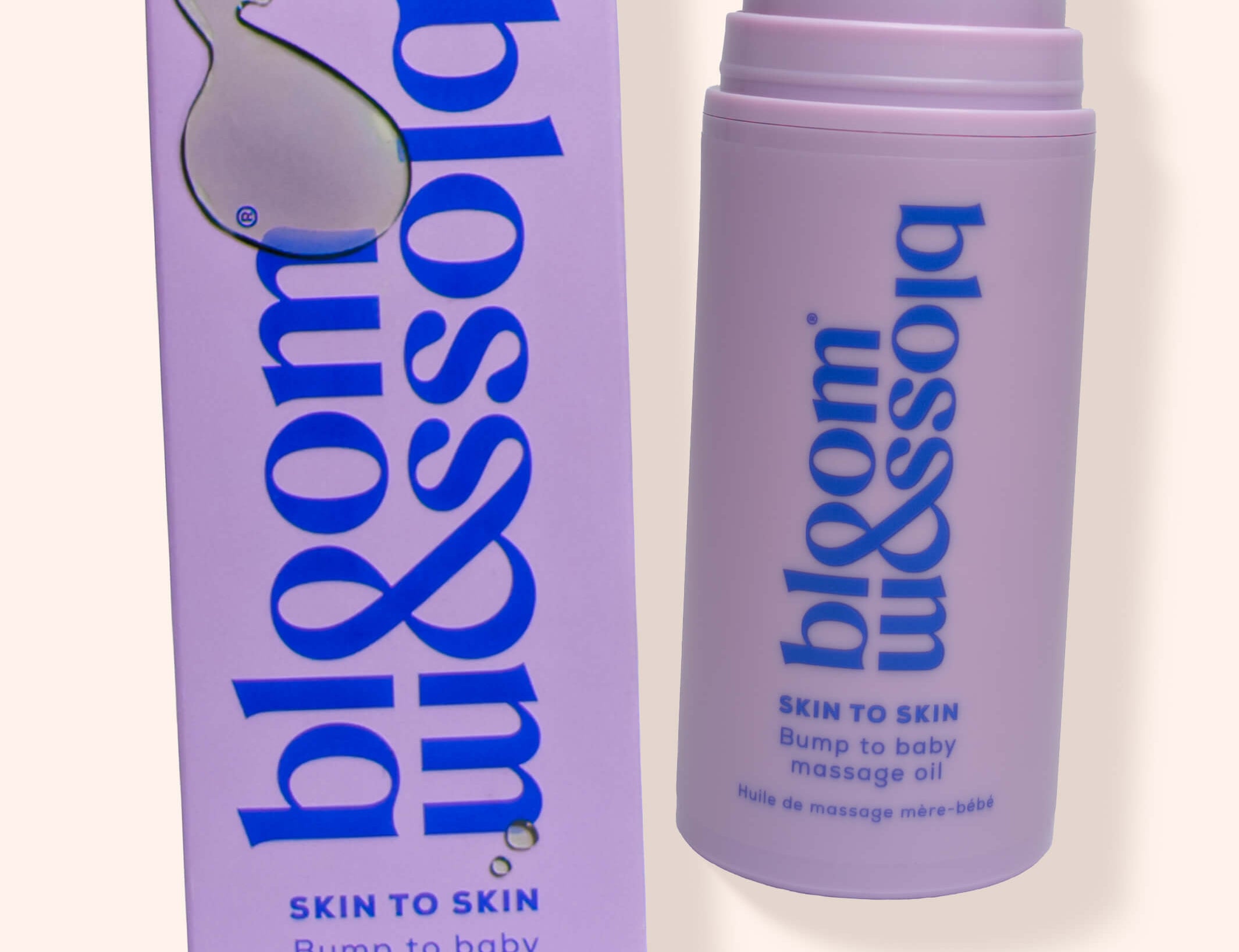 A bottle and box of bloom & blossom Skin to Skin Bump to Baby Massage Oil, shown on a warm off-white background. The packaging is lavender purple with blue text and a white droplet logo.