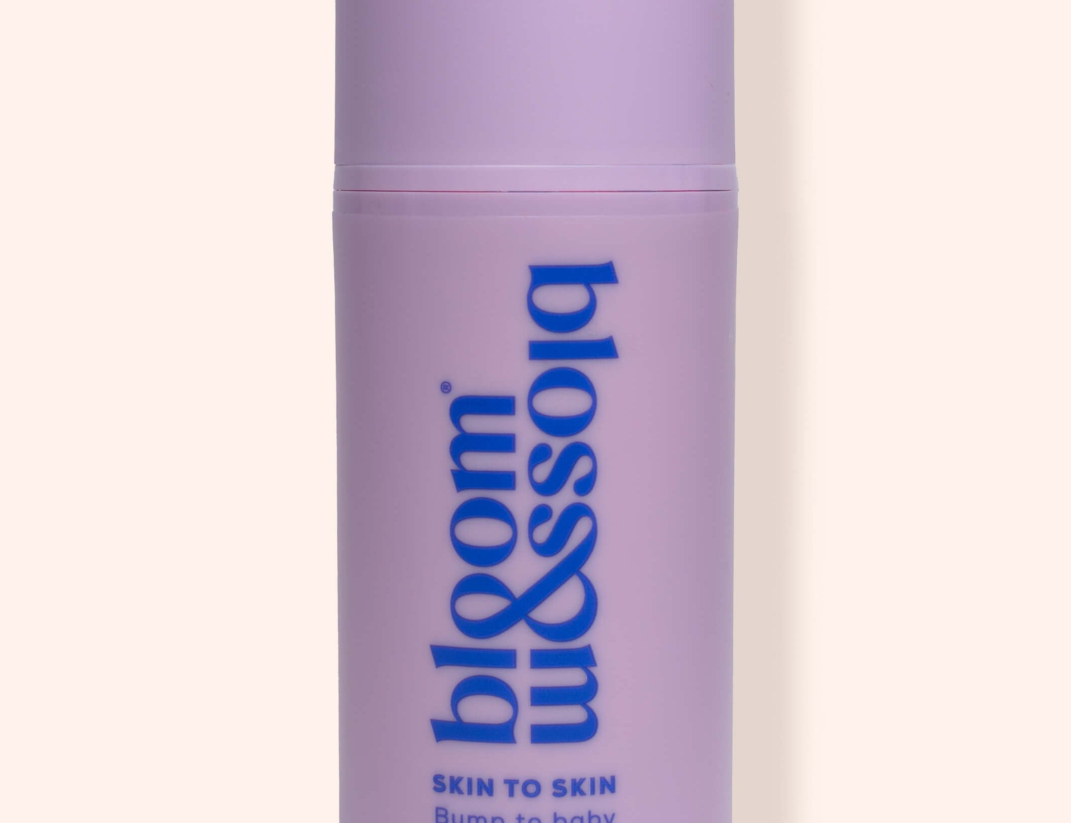 A lavender purple cylindrical bottle of bloom & soft Skin to Skin Bump to Baby Massage Oil, featuring blue text on a clean, solid, light cream background.