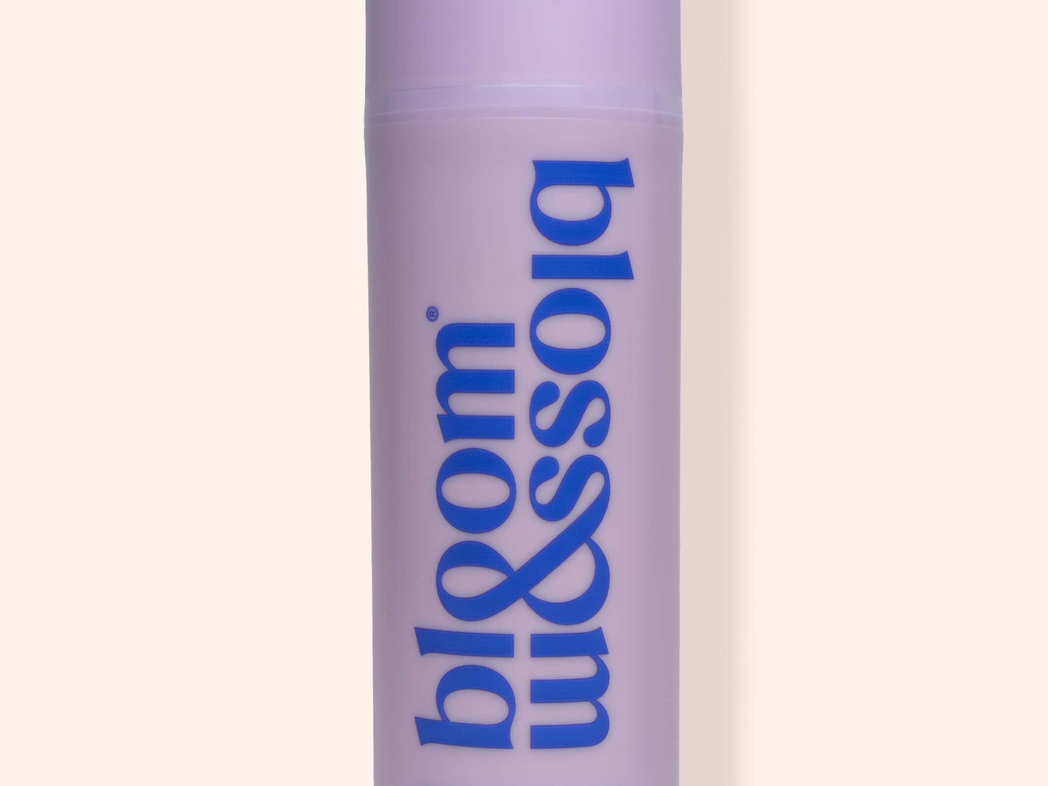 A lavender purple cylindrical bottle of bloom & soia Stretch mark oil, featuring blue text, set against a solid pale beige background with a soft shadow.