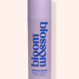 A lavender purple cylindrical bottle of bloom & soia Stretch mark oil, featuring blue text, set against a solid pale beige background with a soft shadow.
