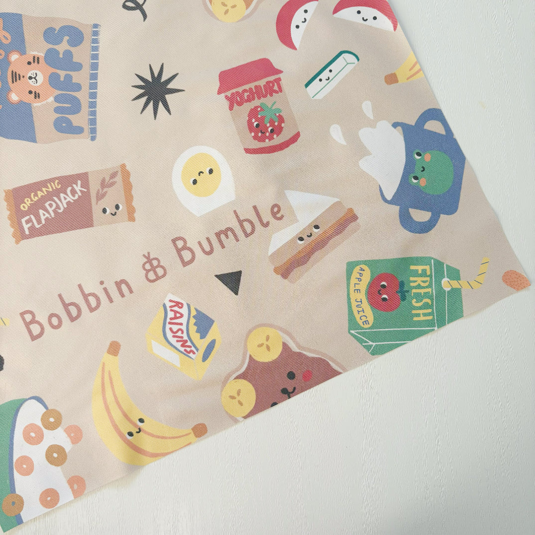 Splash Mat Snack Time, close-up of a corner showing the snack characters pattern and Bobbin and Bumble name on beige