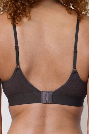 Back view of a woman wearing a dark charcoal ribbed underwire bra with adjustable shoulder straps and a center hook-and-loop closure.