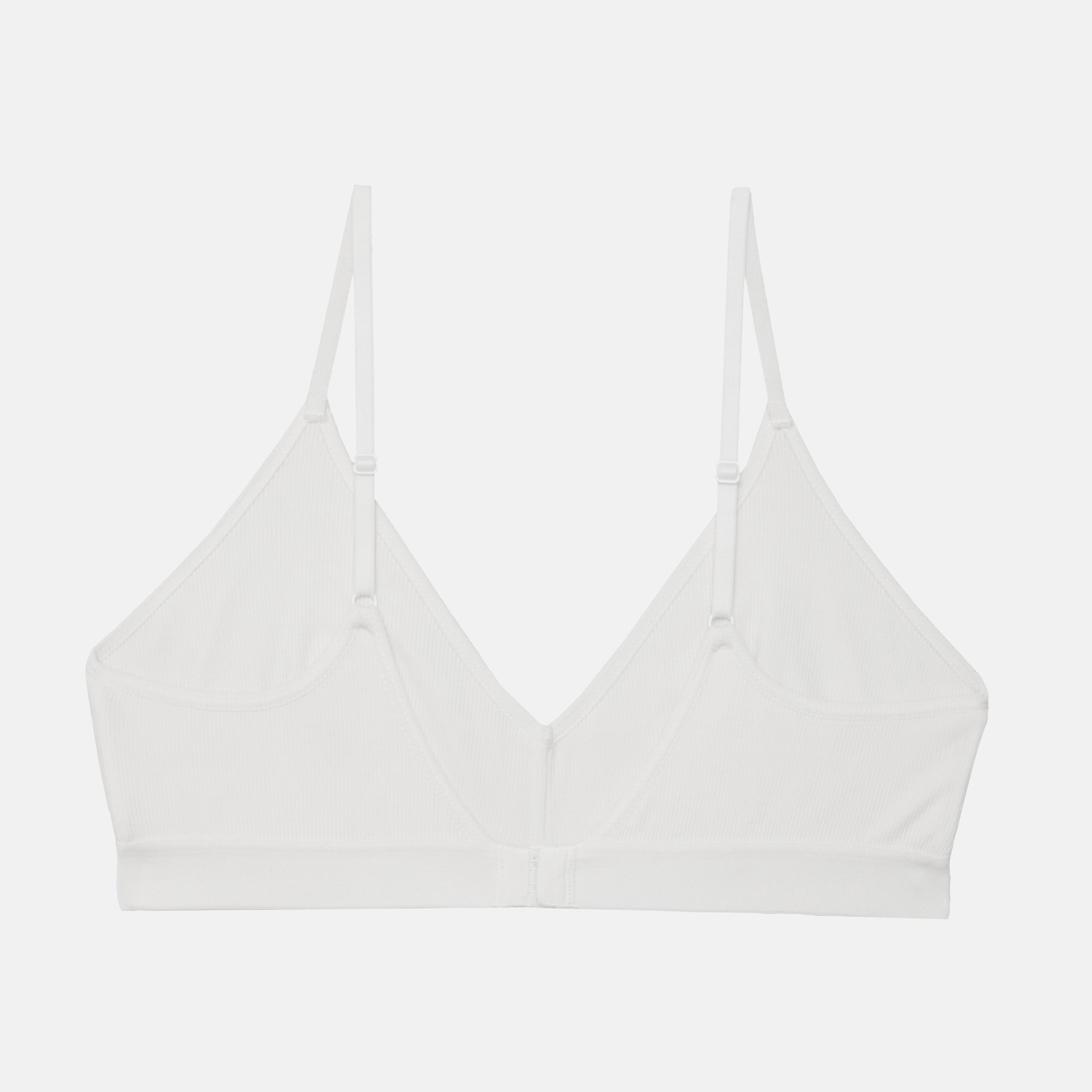 A white wireless triangle bralette with thin adjustable shoulder straps and a center front closure, shown flat against a light gray background.