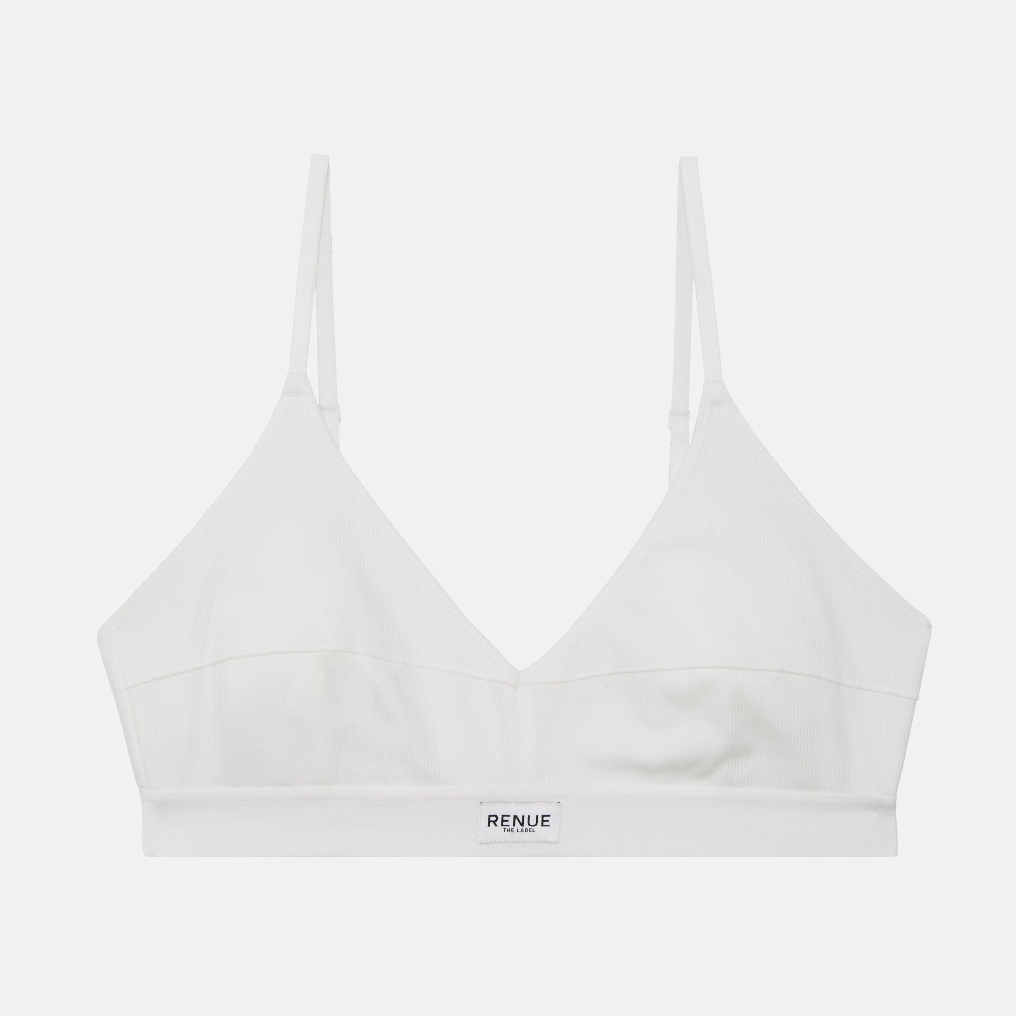 A white wireless bralette by RENUE, featuring thin adjustable shoulder straps and a wide underband with the brand name printed in black, shown against a light gray background.