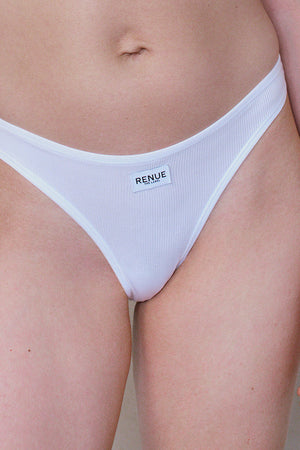 White ribbed thong-style underwear worn by a model, featuring a small white brand label that reads 'RENUE PARIS'.