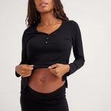 Woman wearing a black long-sleeve top and pants against a white background