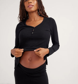 Woman wearing a black long-sleeve top and pants against a white background