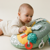 Sophie la girafe Cosy Play Cushion, baby lying on tummy over the cushion and holding the yellow star toy