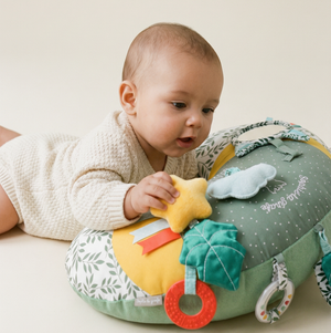 Sophie la girafe Cosy Play Cushion, baby lying on tummy over the cushion and holding the yellow star toy