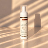 Lusso Tan tinted self tanning mousse, Ultra Dark bottle in warm sunlight with striped shadows on a beige surface