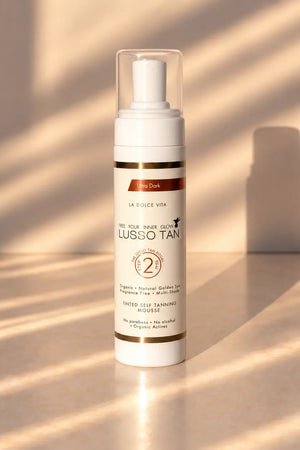 Lusso Tan tinted self tanning mousse, Ultra Dark bottle in warm sunlight with striped shadows on a beige surface
