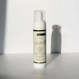 Lusso Tan tinted self tanning mousse, Medium shade bottle with green label stripe, standing in sunlight on a white surface