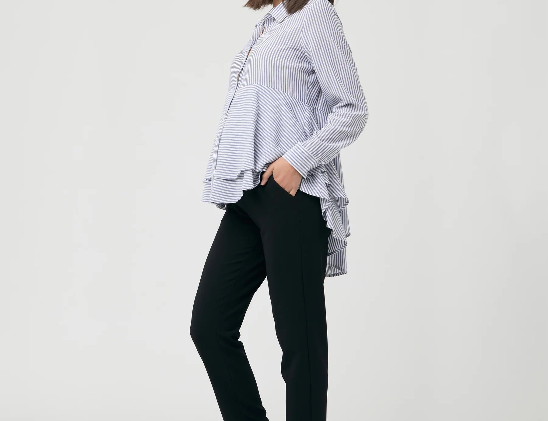 Woman wearing a striped shirt and black pants on a white background