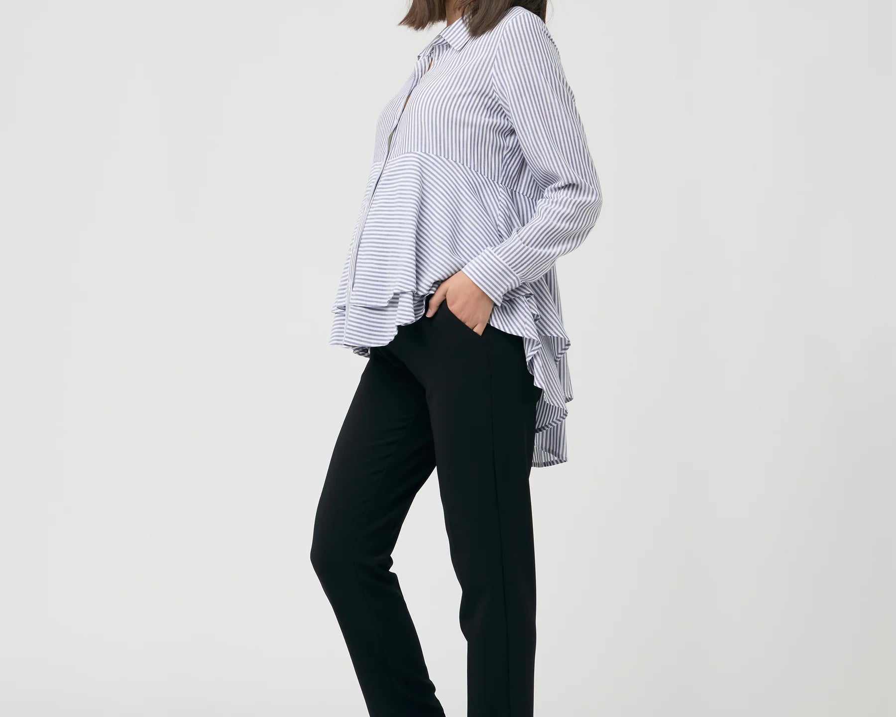 Woman wearing a striped shirt and black pants on a white background