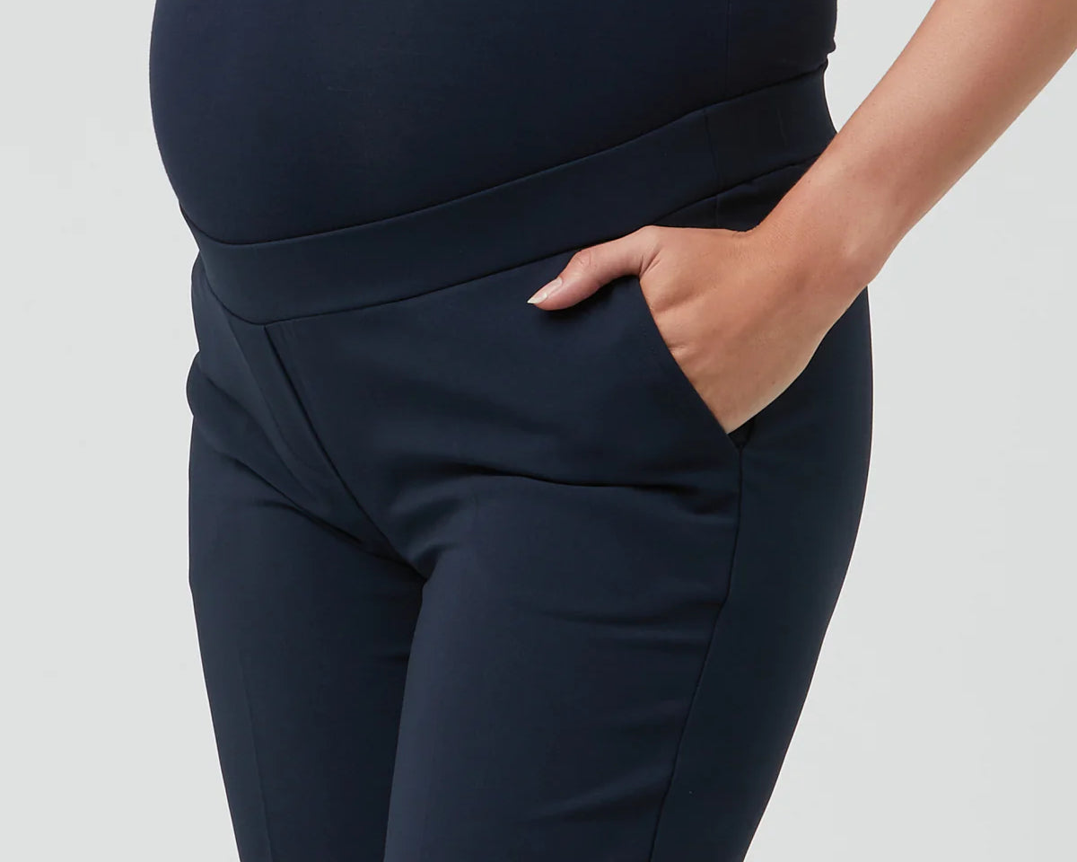 Navy blue maternity pants worn by a person on a light gray background