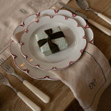 Decorative table setting with a small gift box on a plate, surrounded by cutlery and a napkin.