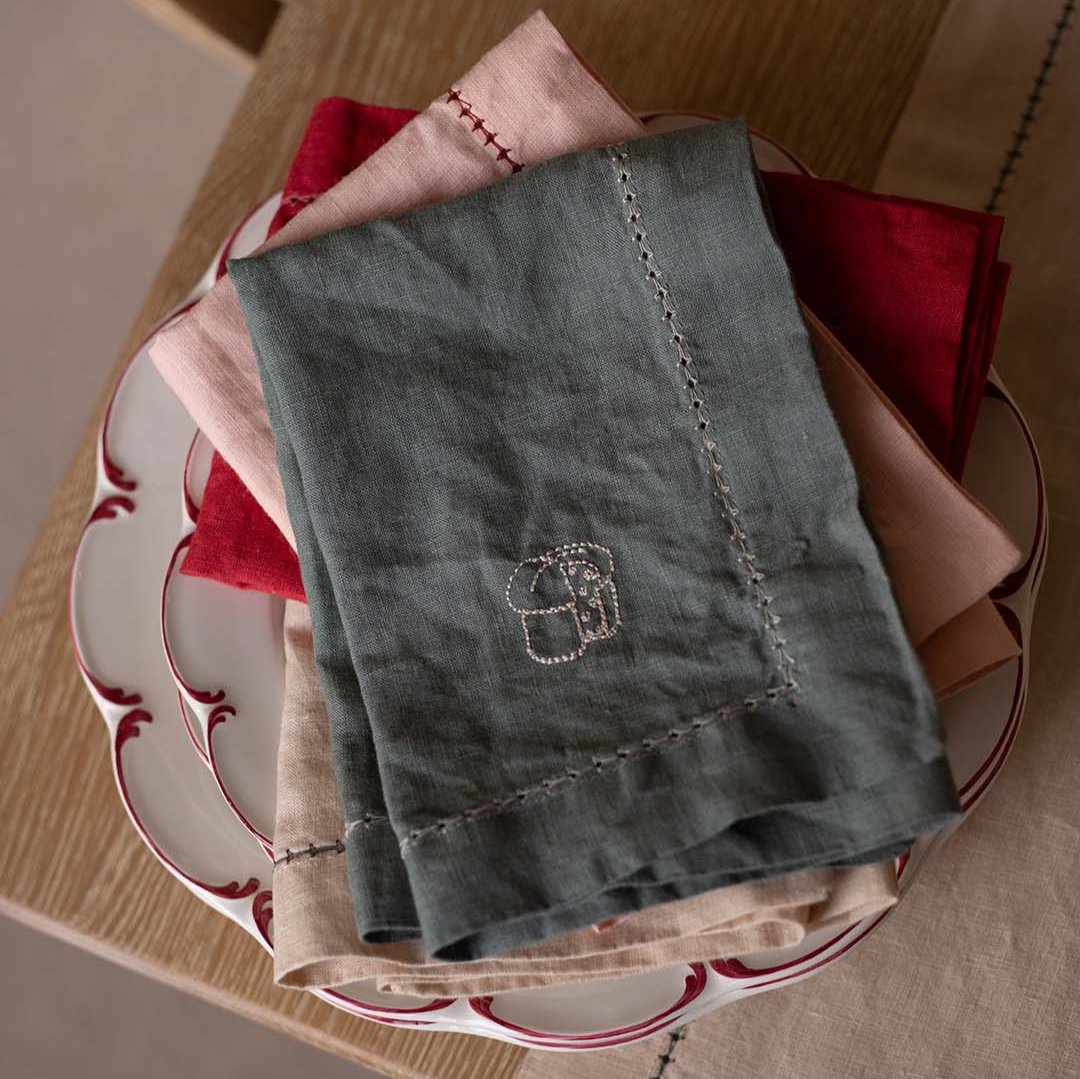 Green embroidered towel on a stack of red and white patterned plates