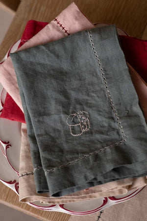 Green embroidered towel on a stack of red and white patterned plates