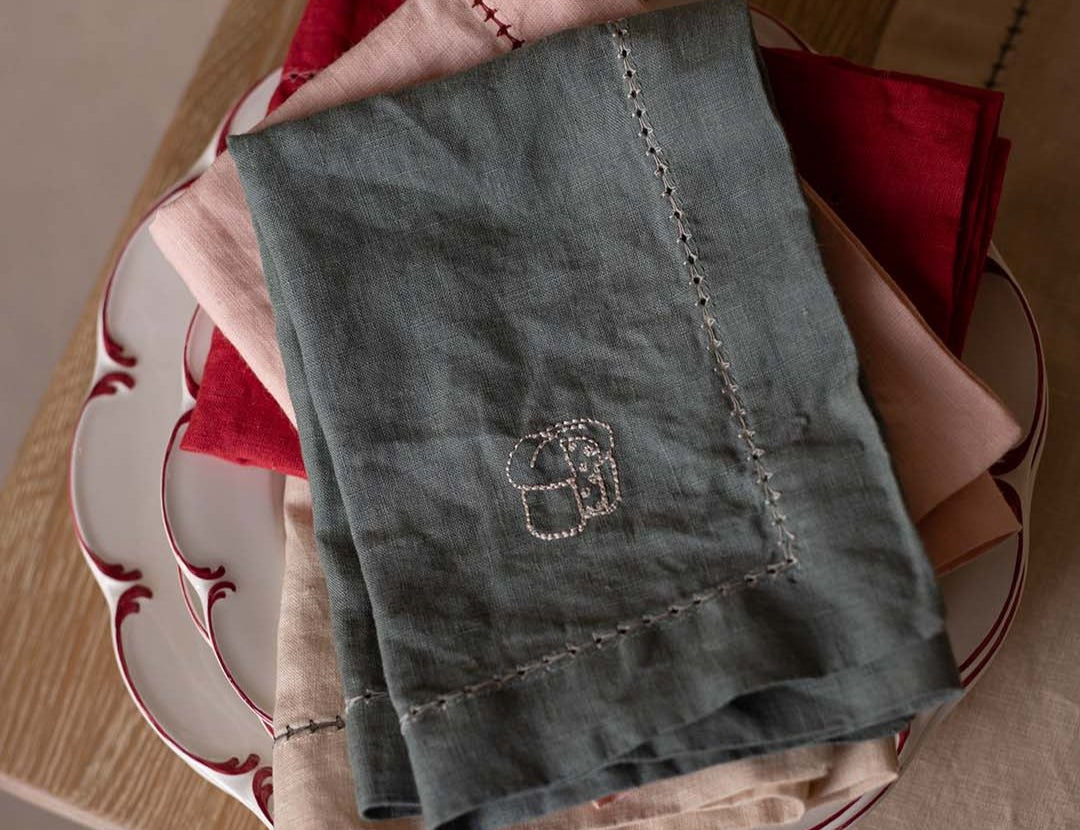 Green embroidered towel on a stack of red and white patterned plates
