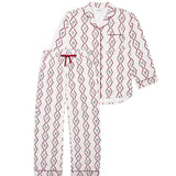 A two-piece pajama set featuring a long-sleeve button-up top and matching pants, both in white with a red and green diamond-patterned print. The top has a red piping border and a red drawstring tie at the collar, while the pants have a matching red piping border and cuffs.
