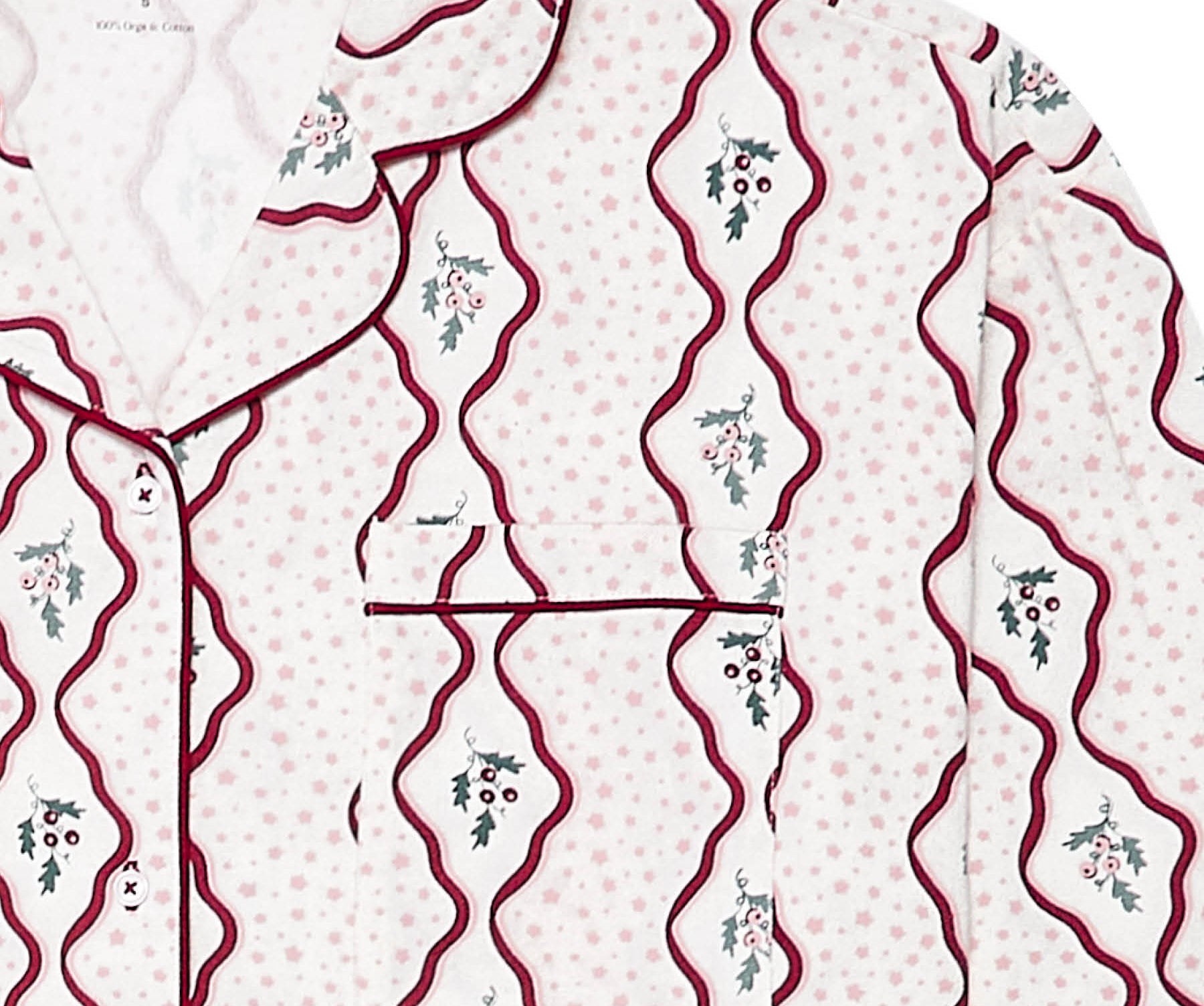A close-up of a pajama shirt by Avery Row, featuring a white base with light pink polka dots, dark red wavy vertical lines, and small green and pink floral motifs.