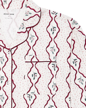 A close-up of a pajama shirt by Avery Row, featuring a white base with light pink polka dots, dark red wavy vertical lines, and small green and pink floral motifs.
