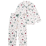 A two-piece children's pajama set with a festive Christmas print, featuring a long-sleeve button-up top and matching pants on a solid white background.