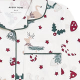 A close-up of a white long-sleeve pajama top with a Christmas print, featuring green piping, a chest pocket, and motifs of reindeer, candy canes, mistletoe, and red stars. The brand name 'AVERY ROW' is visible on the inner neck label.
