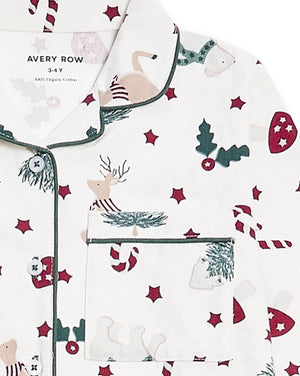 A close-up of a white long-sleeve pajama top with a Christmas print, featuring green piping, a chest pocket, and motifs of reindeer, candy canes, mistletoe, and red stars. The brand name 'AVERY ROW' is visible on the inner neck label.